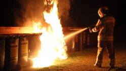 Feuerwehr löscht mehrere Containerbrände Ein Feuerwehrmann löscht einen brennenden Müllcontainer. Symbolbild - Foto: Roland Halkasch